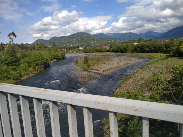 istock Tranquil river meandering through lush green landscapes under a vibrant sky filled with clouds near a peaceful mountain town 2177599404