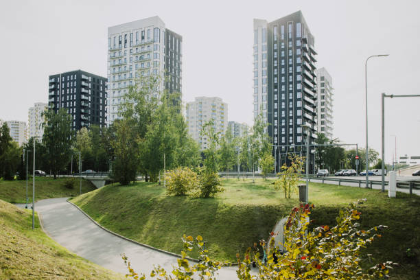 A group of high-rise buildings stands amidst a park with trees and grass, showing how urbanization and nature coexist. The scene captures the juxtaposition of modern architecture with a preserved green space, emphasizing sustainability in city planning and eco-friendly design.