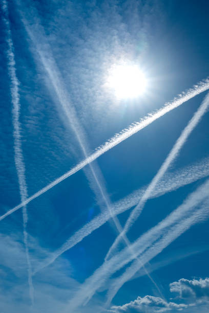 istock Jet Contrails Criss Cross this Bright Blue Sky with Sun Shining above them 2177605600
