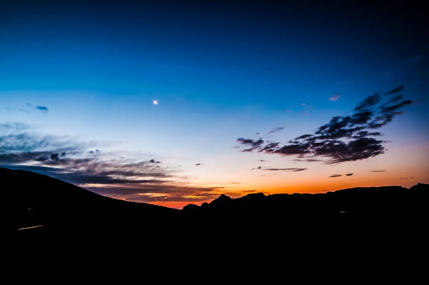 A beautiful sunset with a large moon in the sky. The sky is a deep blue color with a few clouds