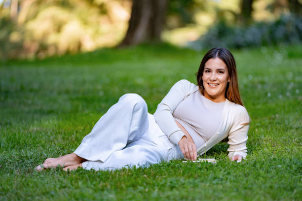 istock Beautiful woman relaxing lying down on the grass in a park 2177620348