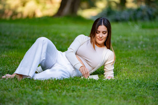 istock Young woman relaxing in the park reading a book 2177620376