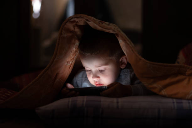 istock Cute boy secretly watching video on phone under the blanket 2177620700