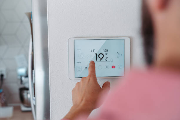 istock Man using smart thermostat, adjusting, lowering heating temperature at home. Concept of smart technology and thermostats in home. 2177622063