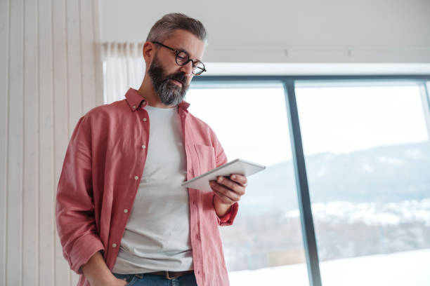 istock Man using smart thermostat, adjusting, lowering heating temperature at home. Smart home controlling roller blinds. 2177622087