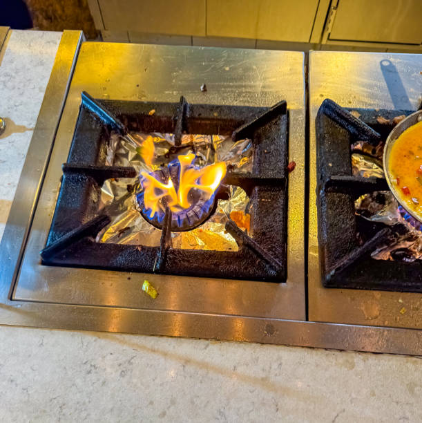 Flames from a gas stove burner heating a pan in a kitchen setting. High quality photo