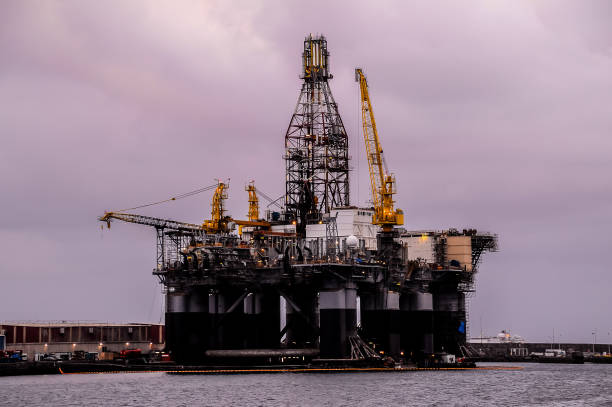 A large oil rig is floating in the ocean. The sky is cloudy and the water is calm