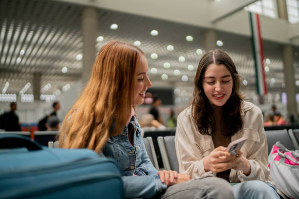 istock Friends women talking and using mobile phone at airport 2177626360