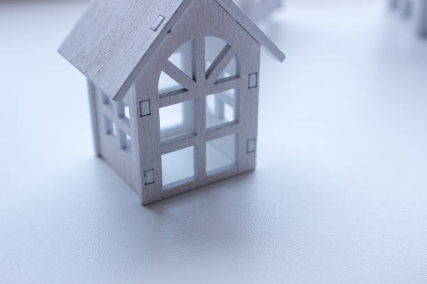 A garland of small wooden houses standing against a neutral background. Each house is intricately carved, creating a rustic and homely ambiance. The natural wood tones contrast nice