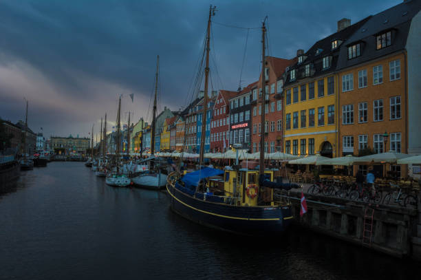 The bow of a charming wooden boat rests peacefully at a Copenhagen waterfront.