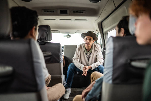 istock Mid adult tour guide talking to tourists inside van 2177629586