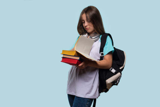istock Serious girl reading book while holding multiple books 2177631732