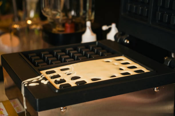 istock Cooking process. Food preparation. Making Belgian waffles. Dough poured into waffle maker in kitchen at home. Breakfast. Liquid dough poured waffle iron machine to prepare Belgian waffle. 2177634331