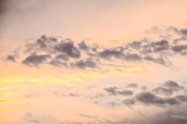 The sky is filled with clouds and the sun is setting. The clouds are white and the sky is a mix of pink and blue