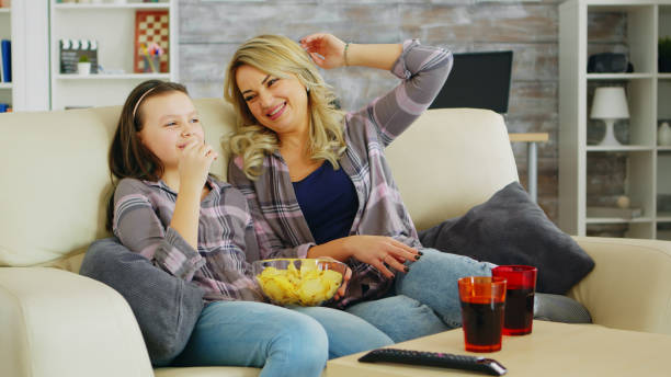 istock Little girl eating chips while watching movie on tv 2177639577