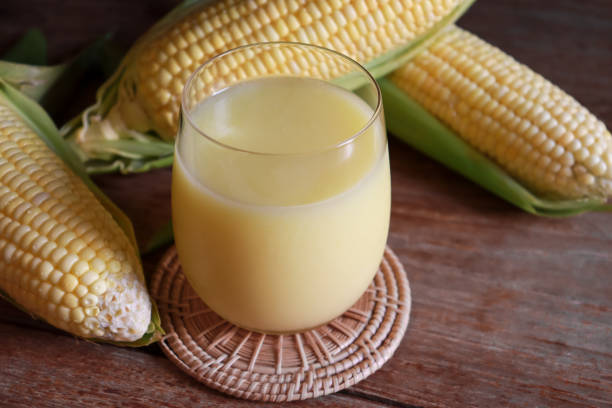 Glass of corn milk with fresh organic sweet corn on rustic wood table. Non dairy product and vegan drinks.