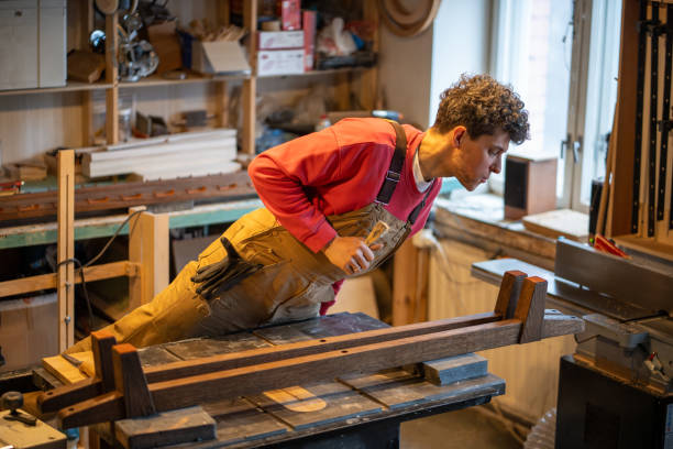 istock Carpenter with chisel check leather pads adhered to bed legs in workshop. Woodwork, small business 2177642035