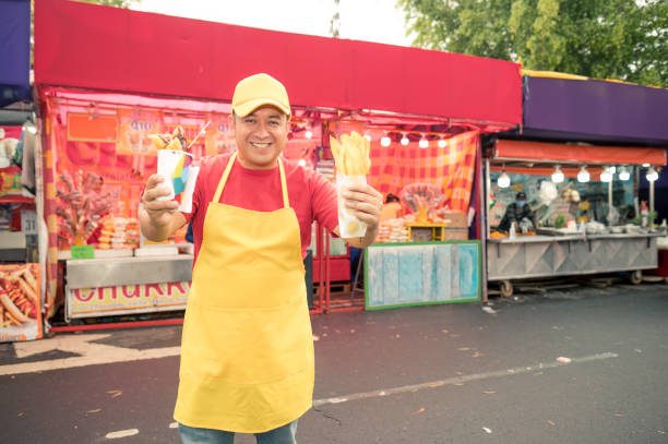 A vendor shows fair visitors the delicious snacks he sells.