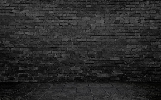 istock dark black concrete perspective room for advertising. stamp concrete floor in grid pattern with rustic black brick wall background. 2177644980