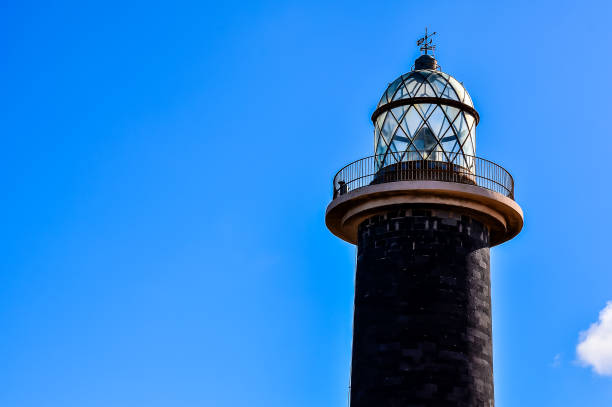 istock A lighthouse is tall and black, with a blue sky in the background 2177645639