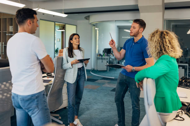 istock A man holds a clipboard in his hands while presenting his business ideas to a smaller group of colleagues at a meeting in the office 2177653945