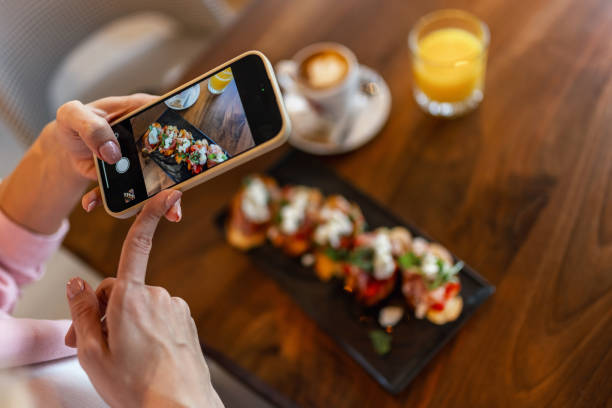 Woman influencer taking pictures of food in a restaurant. Social media. Food and drink concept. stock photo