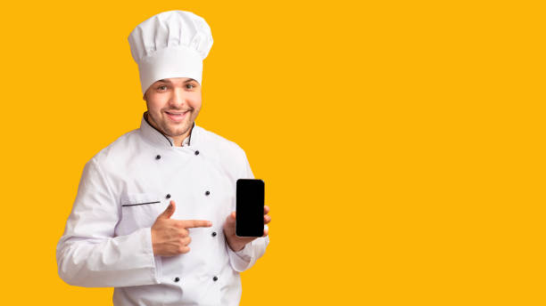 istock Positive Chef Holding Phone With Blank Screen Over Yellow Background 2177661550