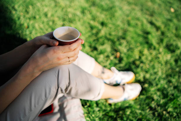 female handsholding a cup of coffee with blurred background.