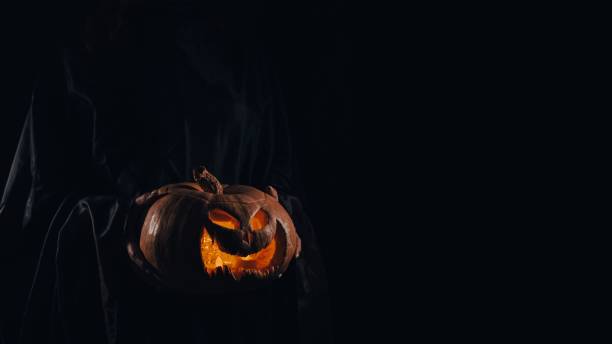 istock The witch is holding a pumpkin jack o lantern glowing in the dark. Halloween. 2177665843