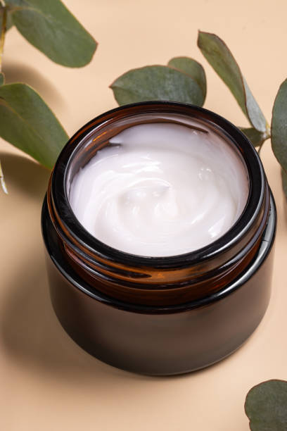 istock face cream on beige background. Dry eucalyptus leaves decoration. Professional bottle for facial and body treatment. Unbranded package 2177667271