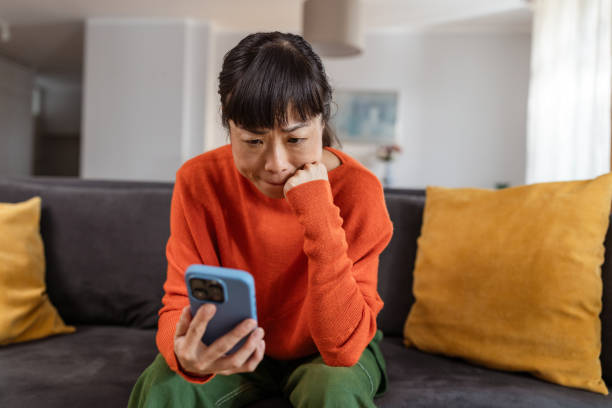 istock Stressed Japanese woman on sofa looking at smart phone 2177668194