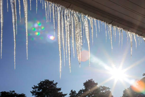 istock Icicles on a roof gutter with lens flare 2177672531
