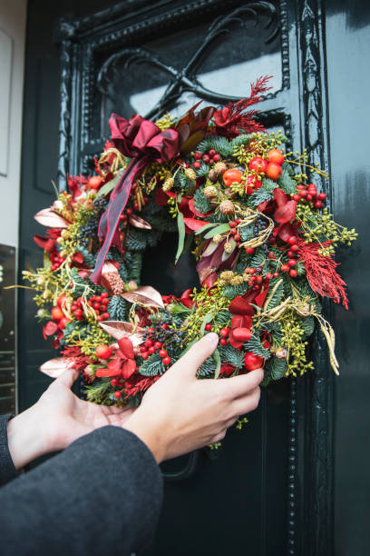 istock Man hanging holiday wreath on front door 2177672917