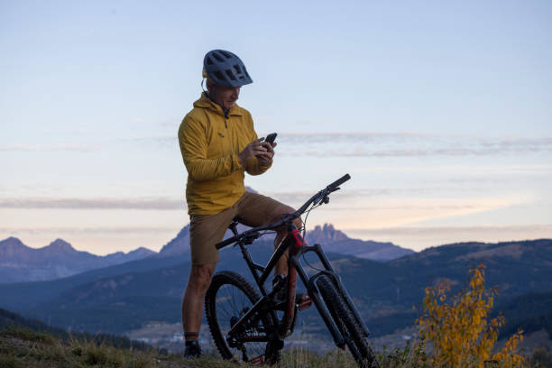 istock Mature man mountain biker uses mobile phone at sunrise 2177679770