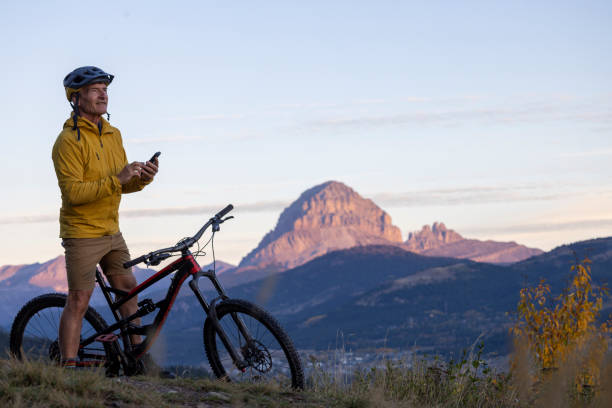 istock Mature man mountain biker uses mobile phone at sunrise 2177679772