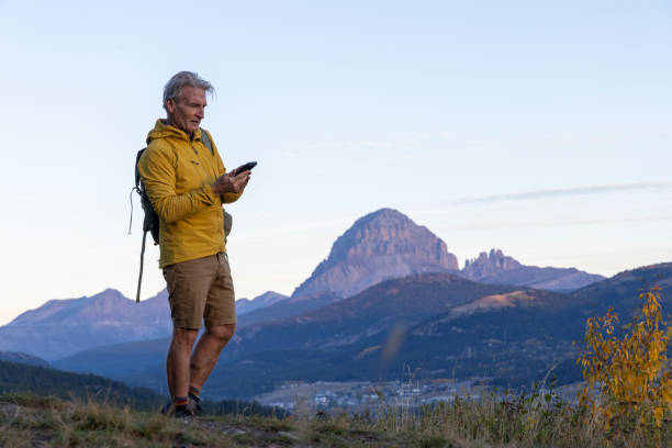 istock Mature man hiker uses mobile phone on mountain path at sunrise 2177679773