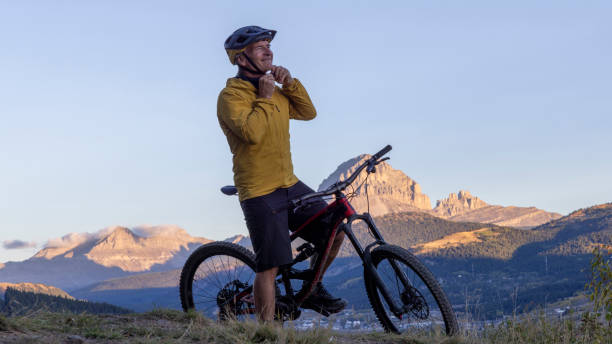 istock Mature mountain biker puts on helmet at sunrise 2177680081
