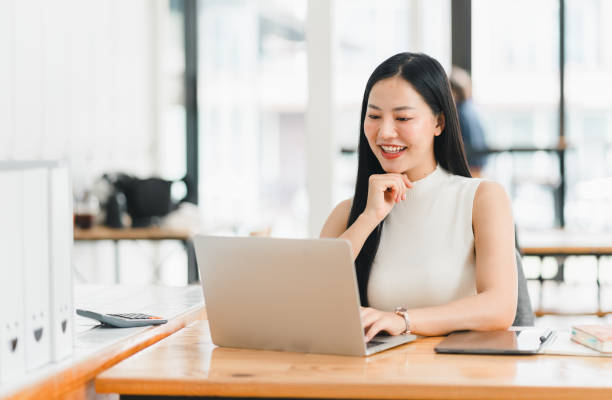 istock A professional woman smiles while working on laptop in modern office. 2177683904