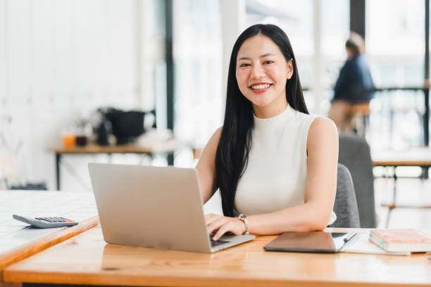 istock A confident woman smiles while working on laptop in modern office. 2177683905