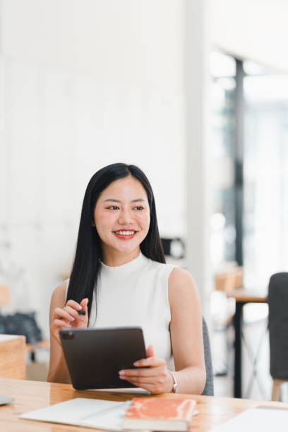 istock A smiling woman using tablet in modern workspace, exuding confidence and focus. 2177683911