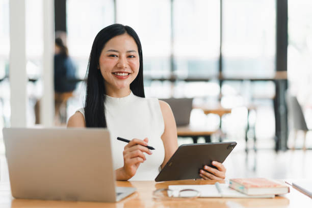 istock A confident woman smiles while working on tablet in modern office. 2177683916