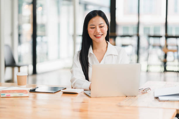 istock A professional woman smiles while working on laptop in modern office. 2177683966