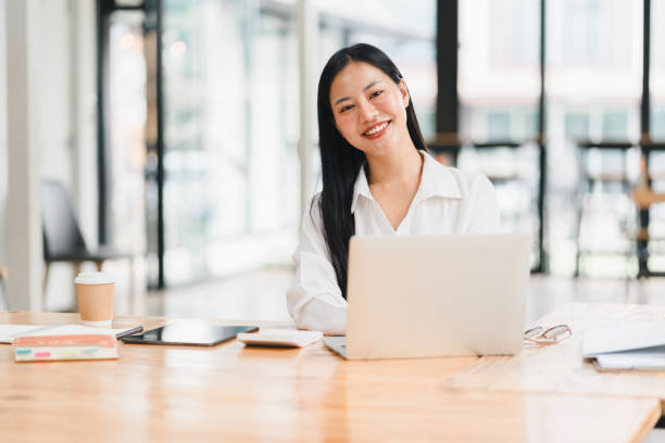 istock A professional woman smiles while working on laptop in bright office. 2177683971