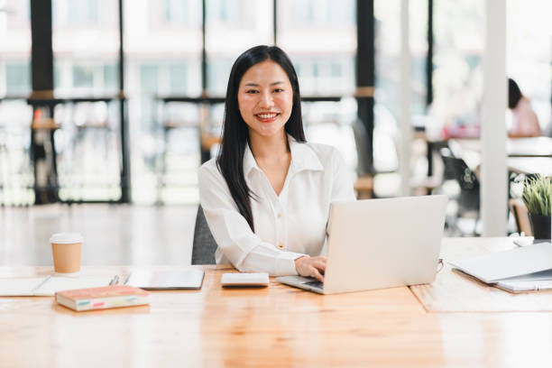 istock A professional woman smiles while working on laptop in modern office. 2177683975