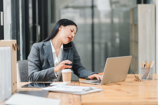 istock Busy woman working on laptop in modern office, multitasking with coffee. 2177684188