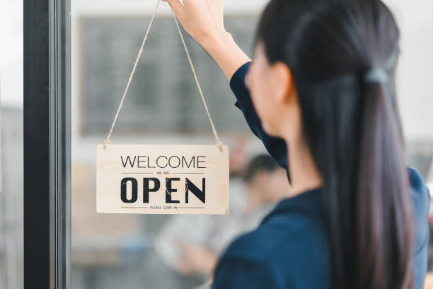 istock Welcome open sign displayed by woman, inviting customers inside. 2177684265