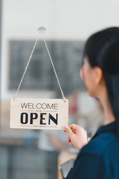 istock Welcome open sign displayed by woman, inviting customers inside. 2177684269