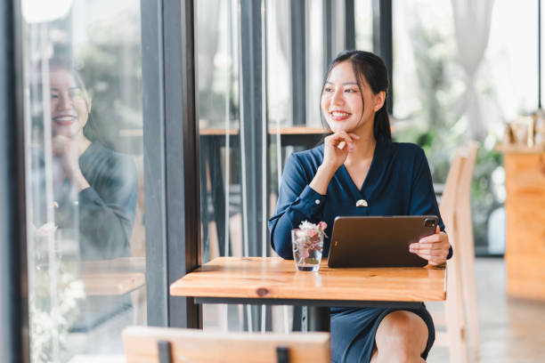 istock A woman in blue dress smiles while sitting at table with tablet. 2177684324
