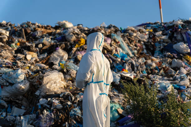 istock Dressed in protective gear, a worker surveys a massive heap of refuse under a clear blue sky, emphasizing the pressing issues of waste disposal and environmental impact 2177691471