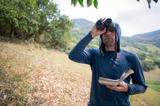 istock Man researches field guide book for bird identification. Man in birding activity. 2177694120